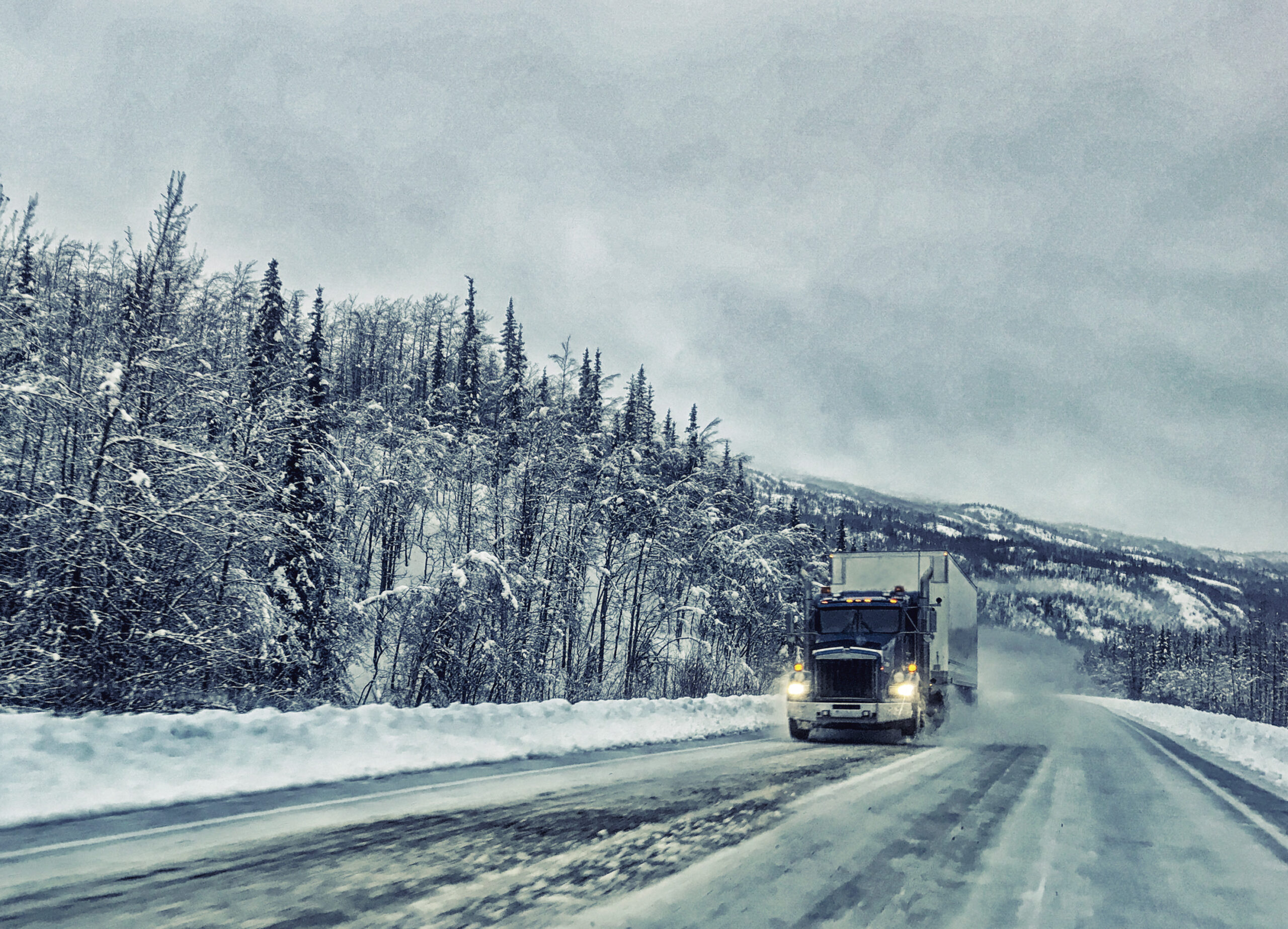 Semi truck driving through a winter storm.